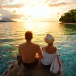 Happy couple on the pier on background colorful sunset